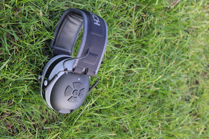 Close-up of Mufftech Double OG earmuff showing padded headband and control buttons, outdoor setting
