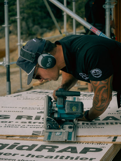 Carpenter cutting roofing with a circular saw while wearing Mufftech Double OG Bluetooth earmuffs