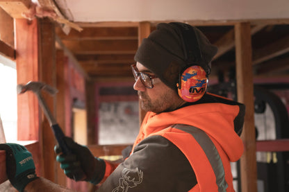 Tradie wearing Mufftech Orange Roughy Bluetooth earmuffs while hammering in a workshop