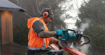 Hi-vis worker operating a Makita grinder while wearing Mufftech Orange Roughy Class 5 hearing protection