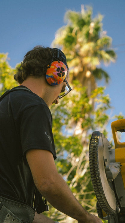 Tradie cutting wood wearing bluetooth earmuffs
