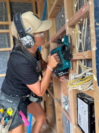 Female tradie using a power tool on site while wearing Mufftech Sole hearing protection