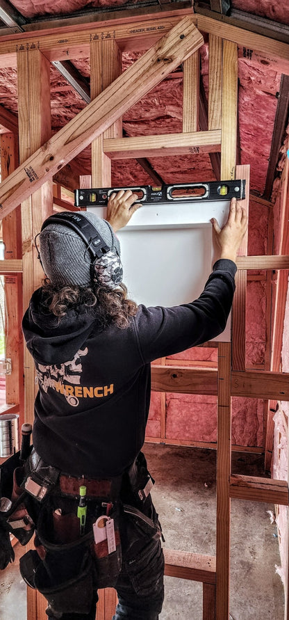 Female builder checking interior framing with a spirit level while wearing Mufftech Sole hearing protection