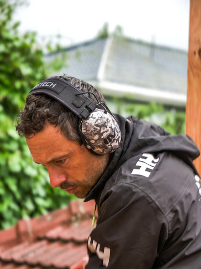 Roofer in wet-weather jacket working on tile roof, wearing Mufftech Sole Class 5 earmuffs